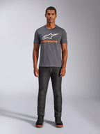 T-shirt Alpinestars Always 2.0 CSF, t-shirt à manches courtes, gris anthracite avec logo blanc et texte orange, porté par un mannequin avec un jean foncé, streetwear motorsport décontracté