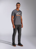 T-shirt Alpinestars Always 2.0 CSF, t-shirt à manches courtes, gris anthracite, logo A-star blanc avec marquage orange, style streetwear décontracté porté avec un jean foncé et des baskets noires