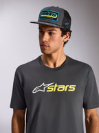 T-shirt Alpinestars Blaze 2.0 CSF, t-shirt à manches courtes, anthracite avec logo blanc et jaune haute visibilité, porté avec une casquette en filet anthracite assortie, sportswear décontracté inspiré des sports mécaniques