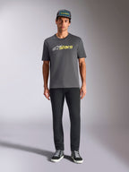 Tee-shirt Alpinestars Blaze 2.0 CSF, t-shirt à manches courtes, gris anthracite avec logo blanc et jaune fluo, porté avec un pantalon noir et une casquette trucker assortie, style motorsport décontracté