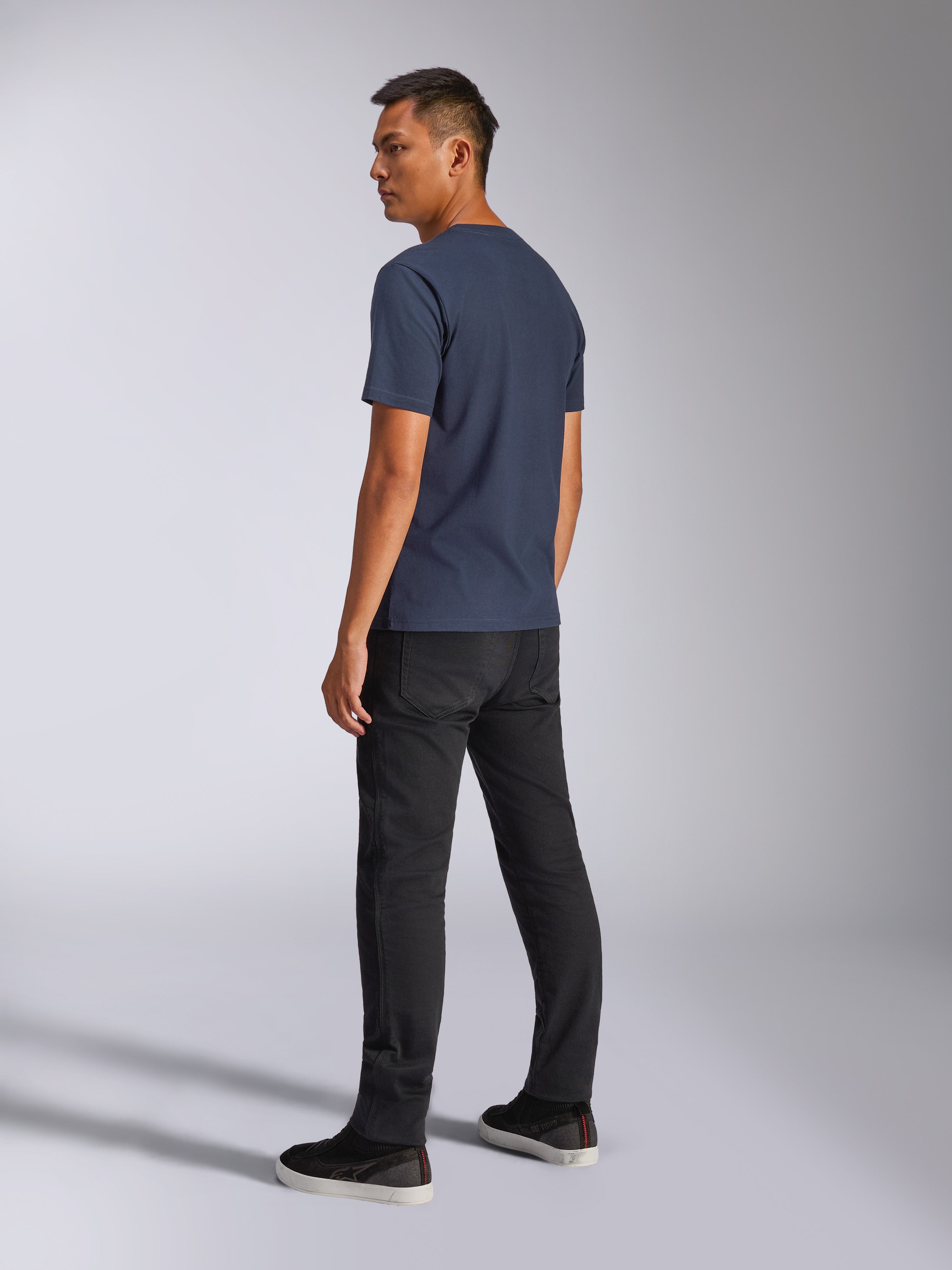 Alpinestars Blaze 2.0 CSF Tee, T-shirt à manches courtes, bleu marine, vue de dos sur modèle, porté avec un pantalon noir et des baskets, streetwear décontracté inspiré par le sport automobile