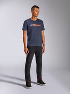 T-shirt Alpinestars Blaze 2.0 CSF, t-shirt à manches courtes, bleu marine avec logo Blaze blanc et orange, porté par un mannequin avec un pantalon noir et des baskets, streetwear décontracté inspiré du sport automobile