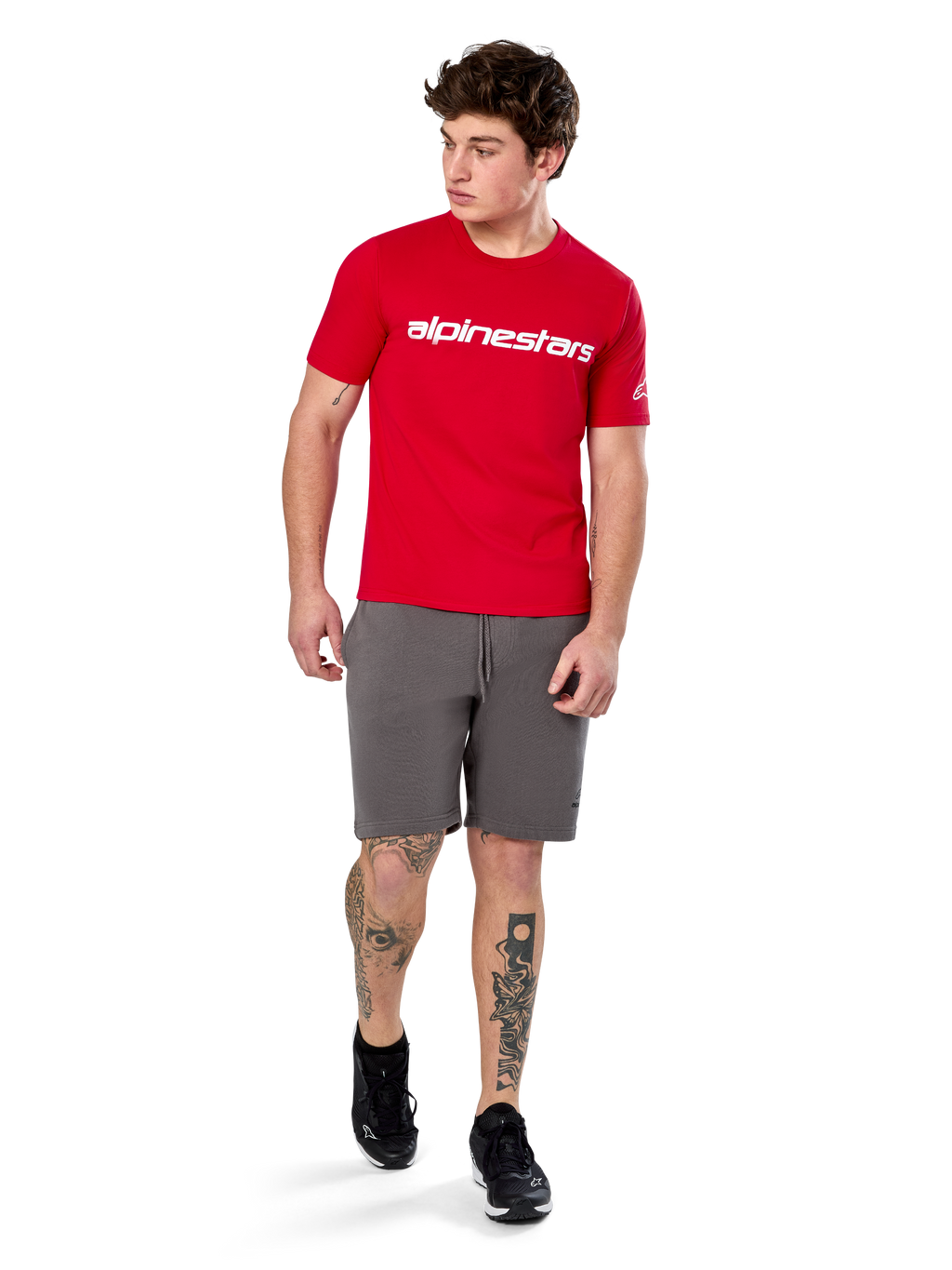 T-shirt Alpinestars Linear Wordmark 2.0 CSF, t-shirt à manches courtes, rouge avec logo mot-symbole blanc sur la poitrine, porté par un mannequin avec un short gris et des baskets noires, streetwear décontracté d'inspiration sport automobile