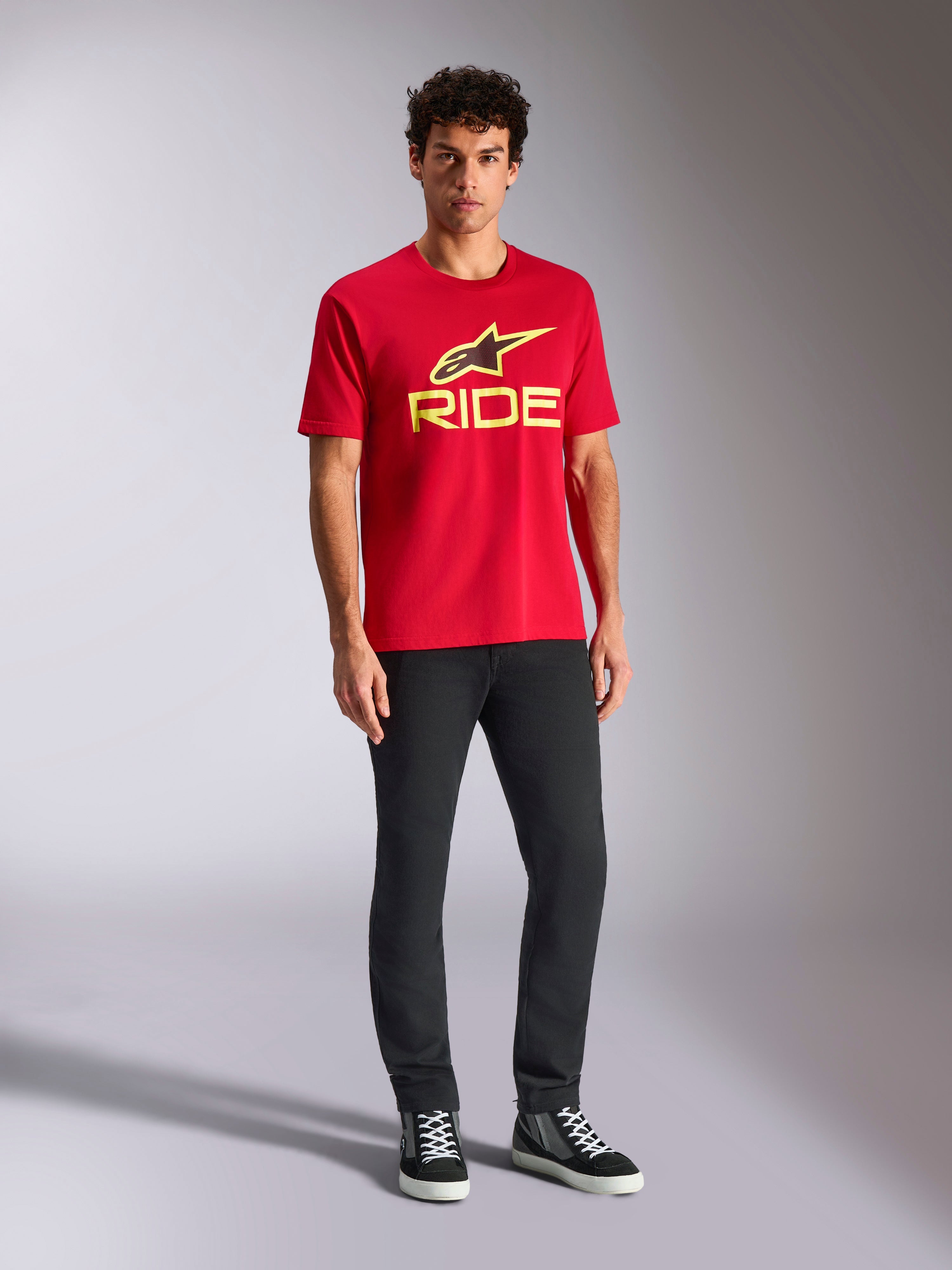 T-shirt Alpinestars Ride 4.0 CSF, t-shirt à manches courtes, rouge avec logo Ride et étoile Alpinestars jaune fluo, porté par un mannequin avec un pantalon noir et des baskets, vêtement sportswear décontracté