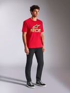 T-shirt Alpinestars Ride 4.0 CSF, t-shirt à manches courtes rouge avec logo frontal jaune et noir, porté avec un pantalon noir et des baskets, style streetwear décontracté motorsport