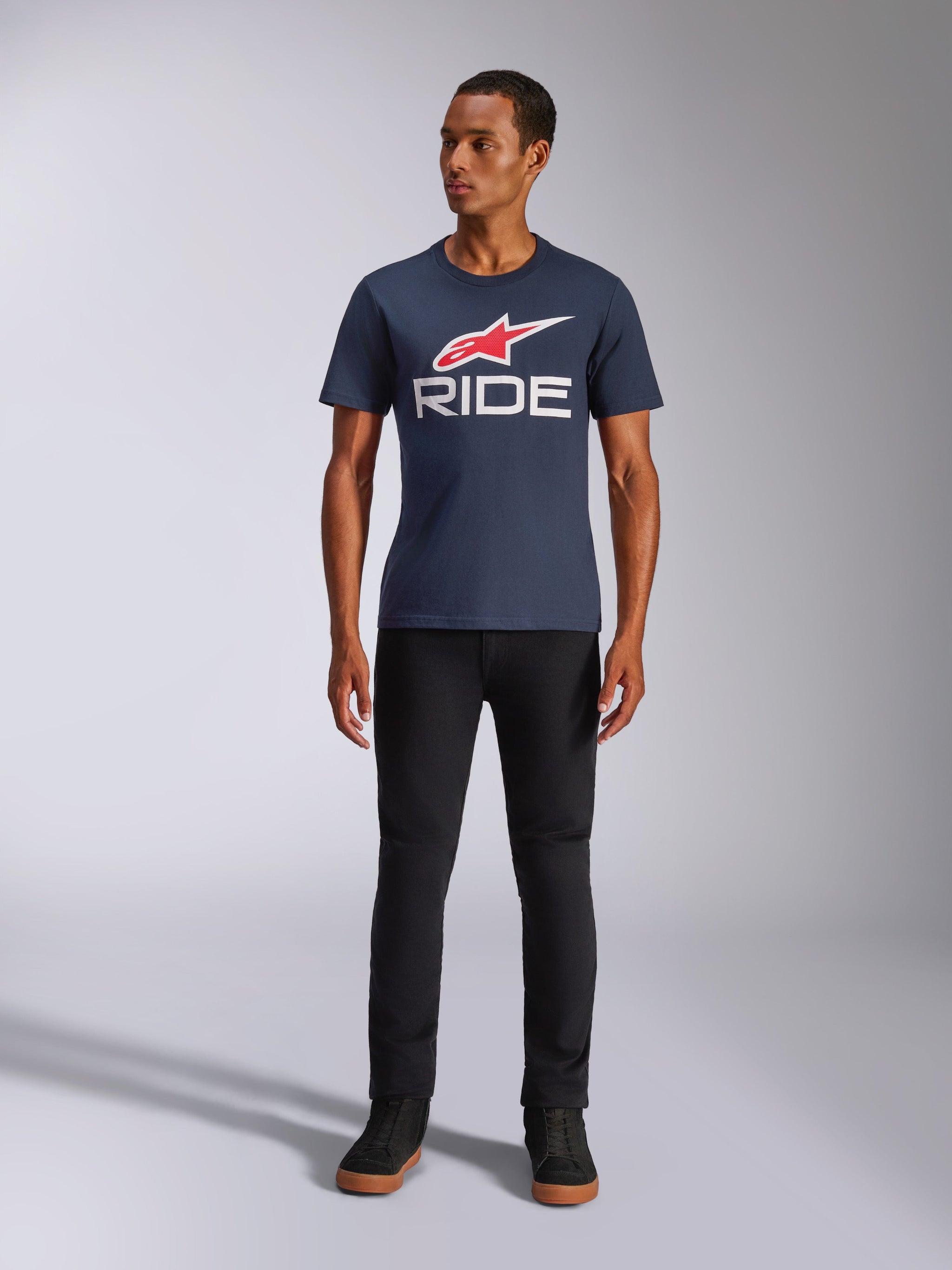 T-shirt Alpinestars Ride 4.0 CSF, t-shirt à manches courtes, bleu marine avec logo étoile Alpinestars rouge et texte 'RIDE' blanc sur la poitrine, porté par un mannequin avec un pantalon noir et des baskets noires, streetwear décontracté inspiré du motorsport
