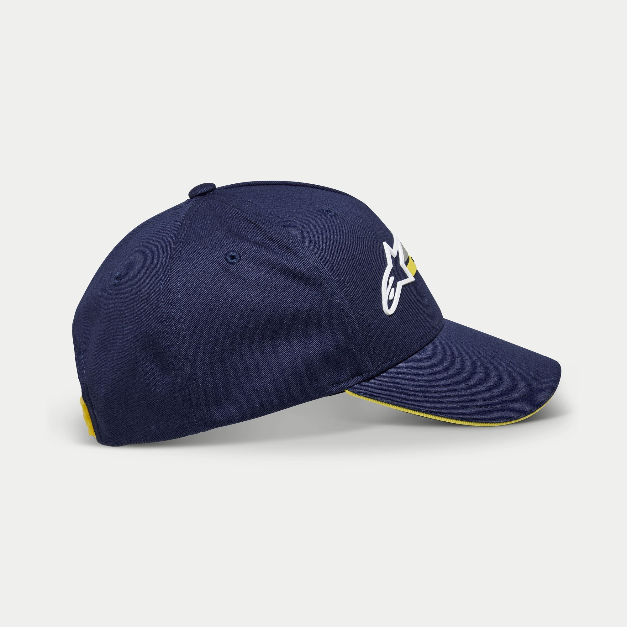 Alpinestars Par Hat, casquette de baseball bleu marine, vue de profil montrant le logo brodé blanc et jaune, visière courbée avec bordure sandwich jaune, couvre-chef structuré décontracté