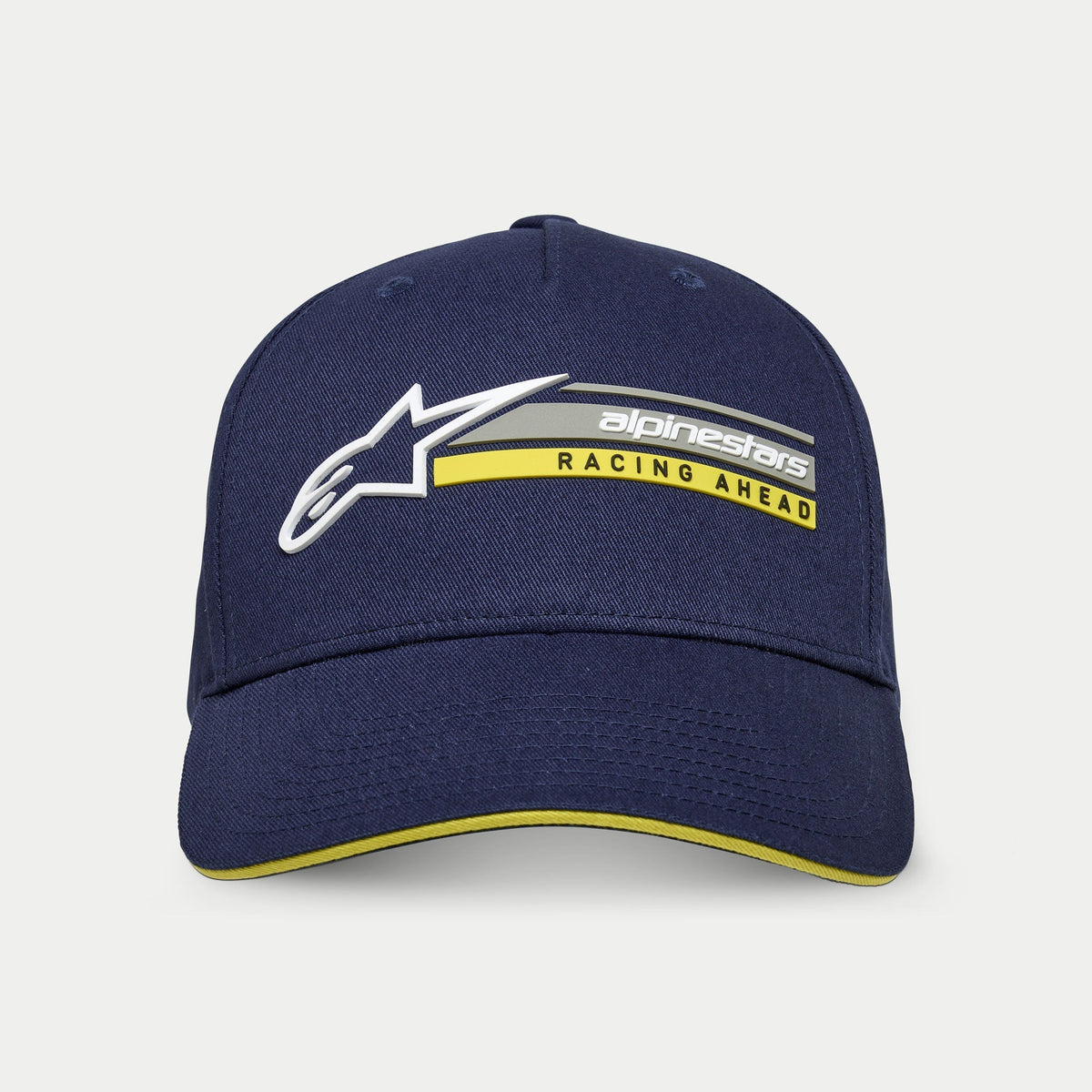 Casquette Alpinestars Par, bleu marine, casquette snapback structurée avec visière courbée, ornée du logo Astars blanc en 3D et du graphisme « alpinestars RACING AHEAD » en gris et jaune, détail de visière sandwich jaune, style motorsport décontracté