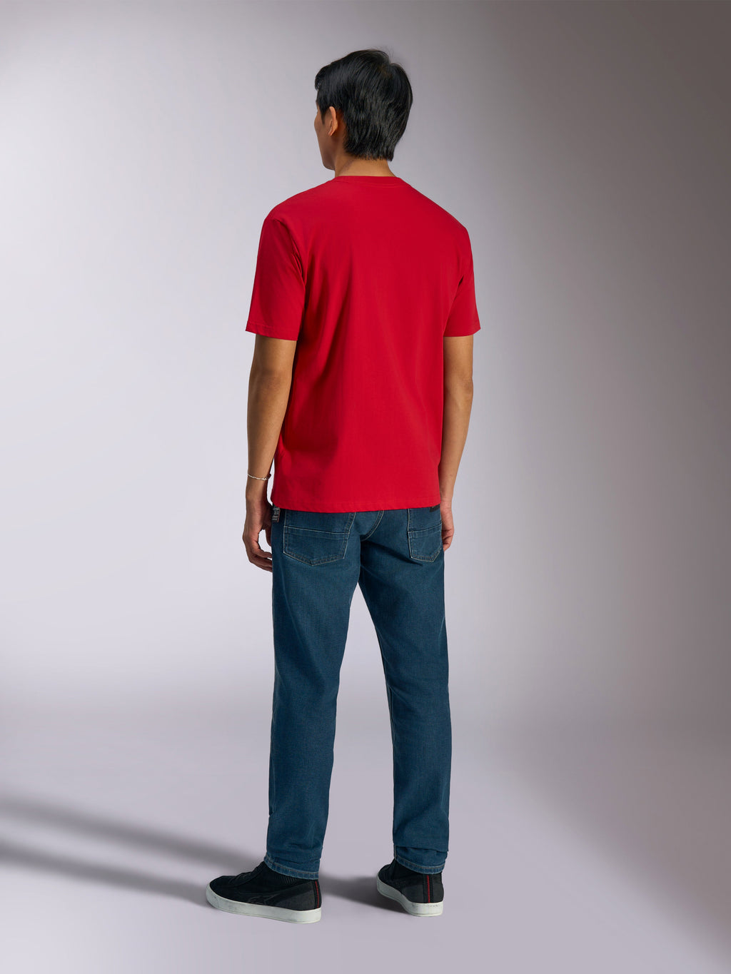 T-shirt Alpinestars Ageless Shadow CSF, t-shirt à manches courtes, rouge, vue de dos porté par un mannequin avec un jean bleu et des baskets noires, style streetwear décontracté inspiré des sports mécaniques