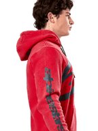 Sweat à capuche Alpinestars Unbound, hoodie en polaire rouge, profil montrant le lettrage Alpinestars gris foncé sur la manche, finition teinte en vêtement avec capuche à cordon de serrage, streetwear décontracté motorsport