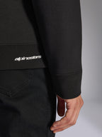 Alpinestars Positive Crew, sweatshirt noir, gros plan sur l'ourlet côtelé et le poignet avec logo Alpinestars blanc, texture de tissu premium, vêtement de sport décontracté d'inspiration sport automobile
