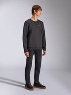Alpinestars Positive Crew, sweat-shirt à col rond, noir, petit logo Alpinestars blanc sur la poitrine, col côtelé avec détail de couture en V, poignets et ourlet côtelés, porté par un mannequin avec un pantalon noir et des baskets, streetwear décontracté inspiré du sport automobile