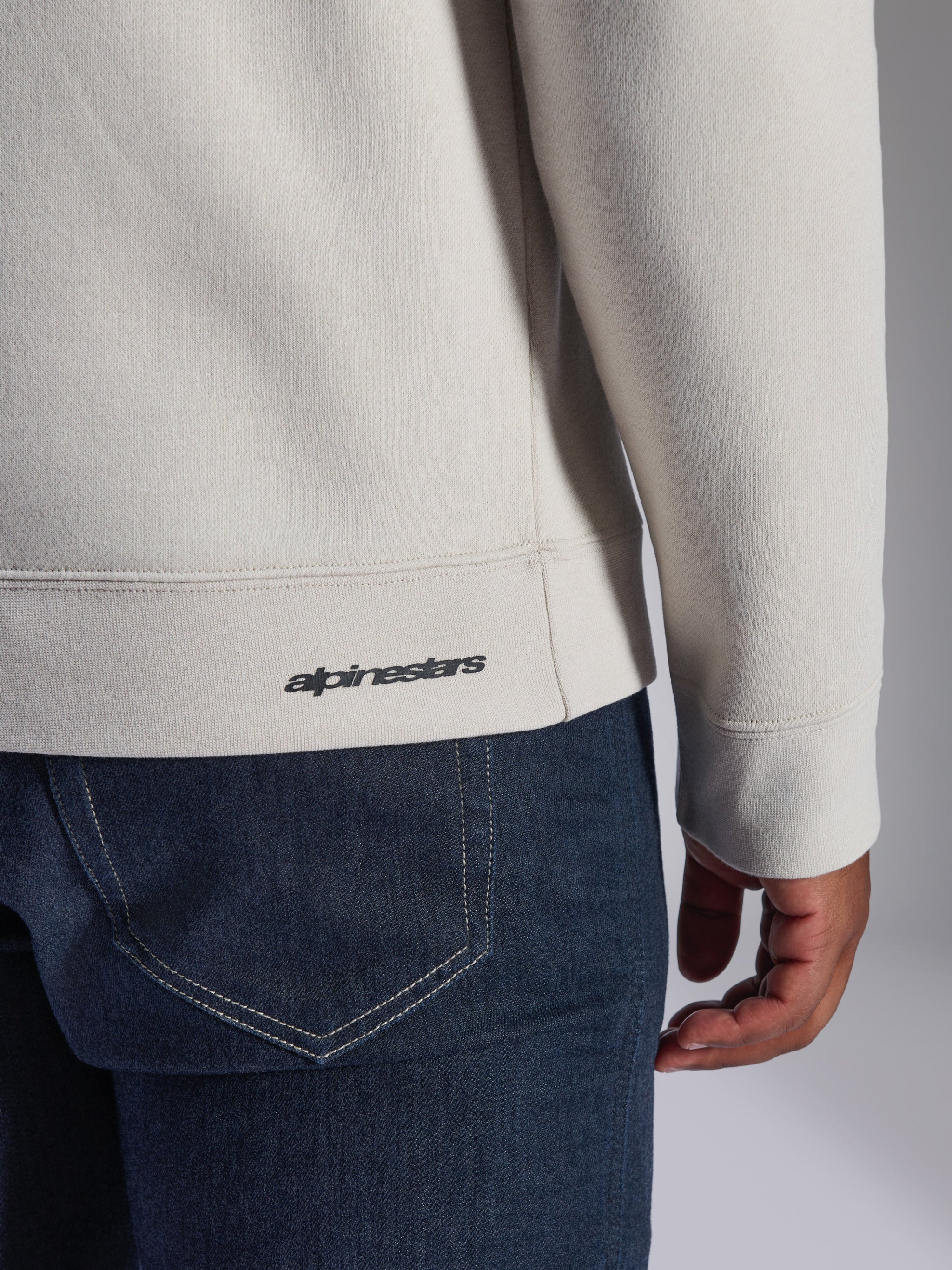 Alpinestars Positive Crew Sweatshirt, blanc cassé, gros plan sur le détail de l'ourlet et du poignet en bord-côte, arborant un petit logo Alpinestars noir, vêtement décontracté d'inspiration sport mécanique
