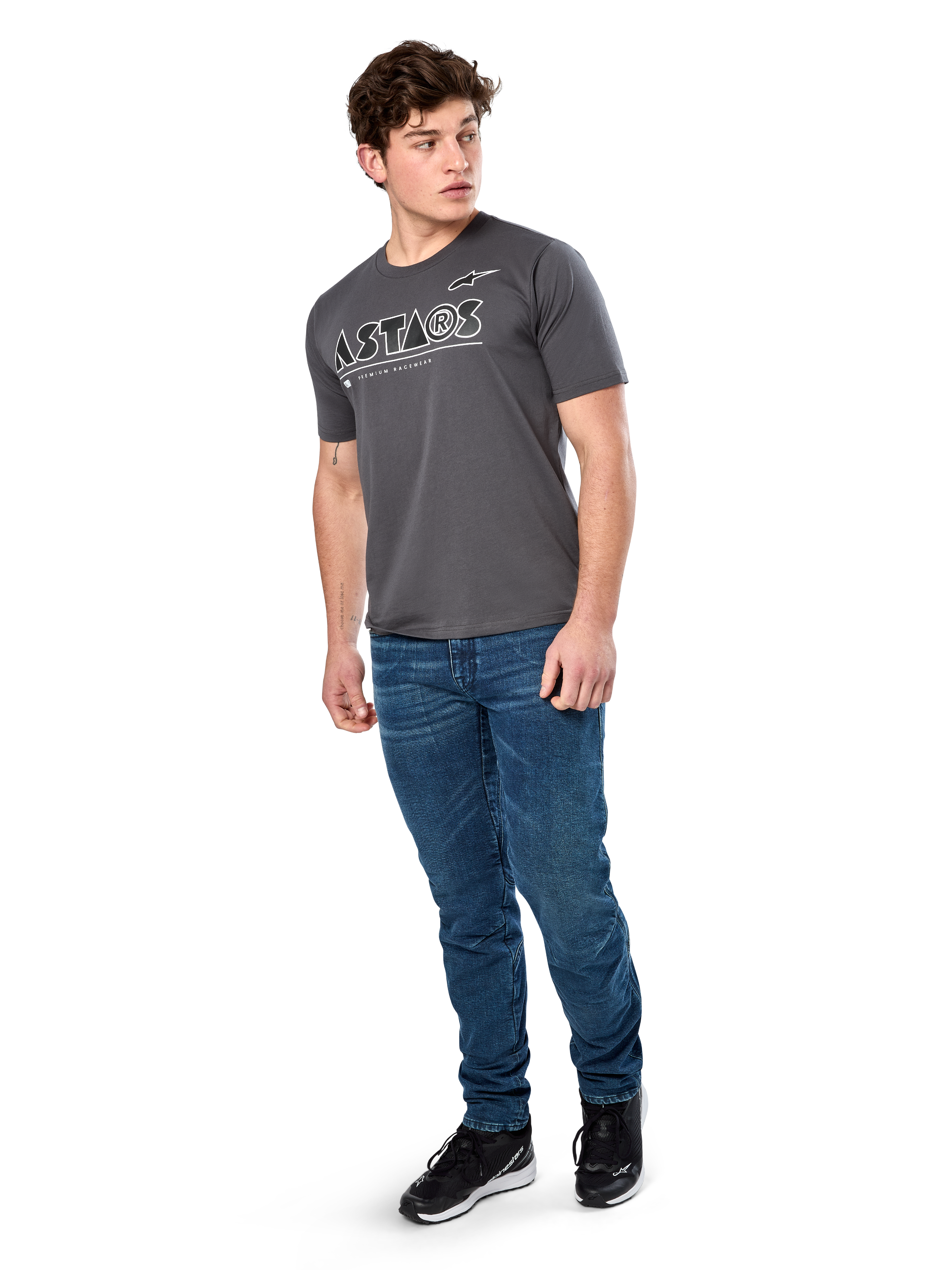 T-shirt Alpinestars Cereal CSF, T-shirt à manches courtes, anthracite, logo texte Astars géométrique blanc, streetwear décontracté style sport automobile porté avec un jean bleu et des baskets noires