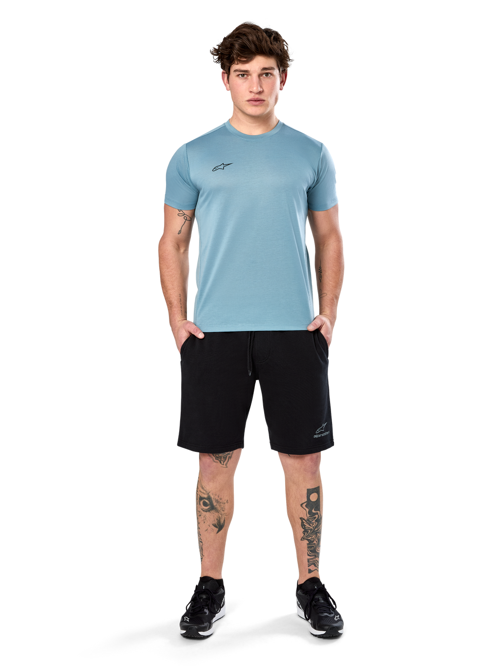 Alpinestars Point Performance Tee, t-shirt à manches courtes, bleu glacier, doté d'un petit logo noir à l'avant et d'un col rond, porté par un mannequin avec un short noir et des baskets noires, vêtement de sport décontracté évacuant l'humidité