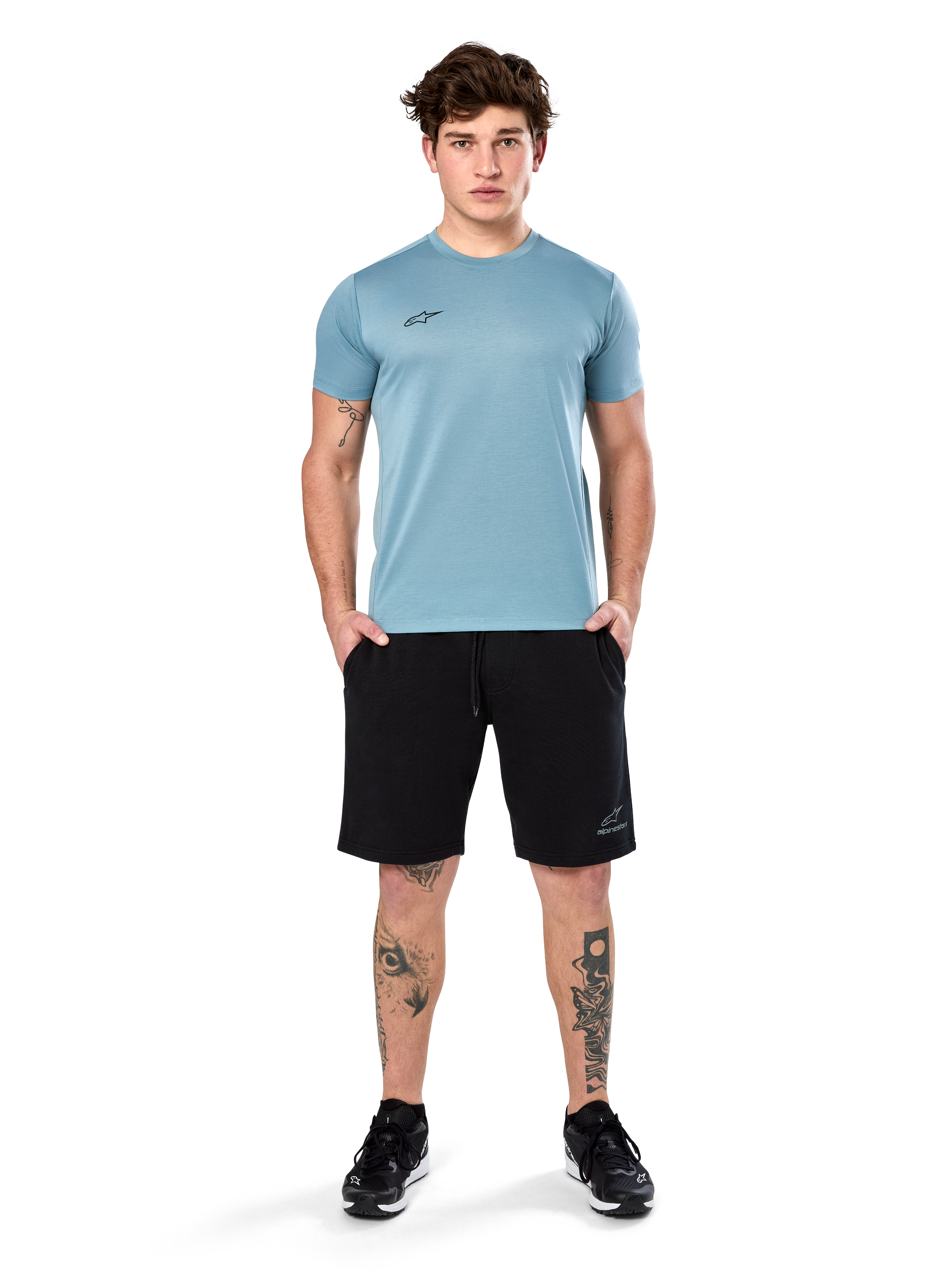Alpinestars Point Performance Tee, t-shirt à manches courtes, bleu glacier, doté d'un petit logo noir à l'avant et d'un col rond, porté par un mannequin avec un short noir et des baskets noires, vêtement de sport décontracté évacuant l'humidité