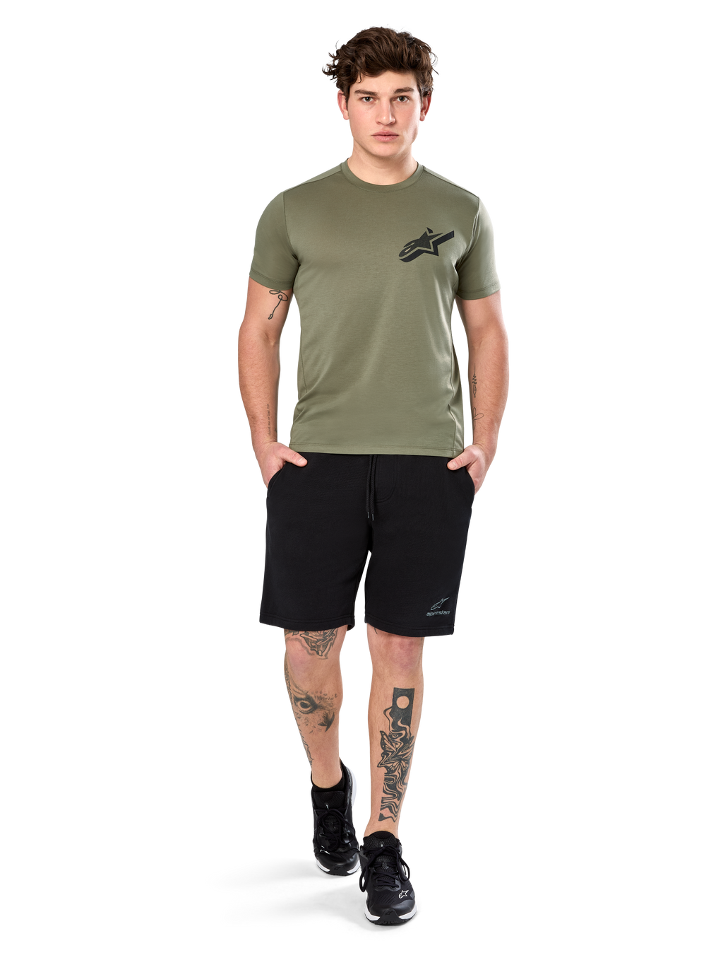 T-shirt Alpinestars Attrition Performance, t-shirt à manches courtes, vert clair, avec logo Astars noir sur la poitrine, porté avec un short de sport noir et des baskets noires, cliché lifestyle sportswear performance décontracté