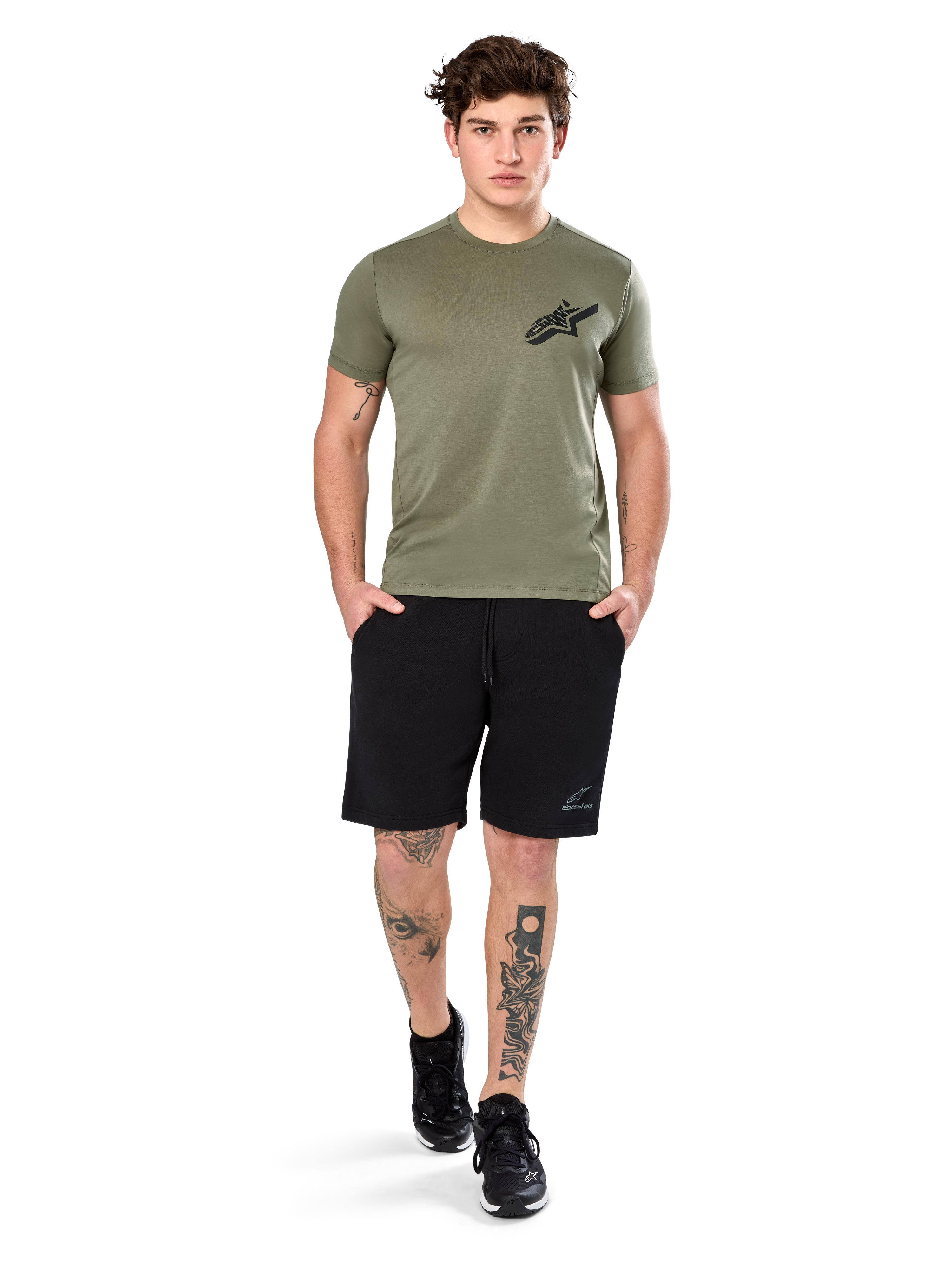 T-shirt Alpinestars Attrition Performance, t-shirt à manches courtes, vert clair, avec logo Astars noir sur la poitrine, porté avec un short de sport noir et des baskets noires, cliché lifestyle sportswear performance décontracté