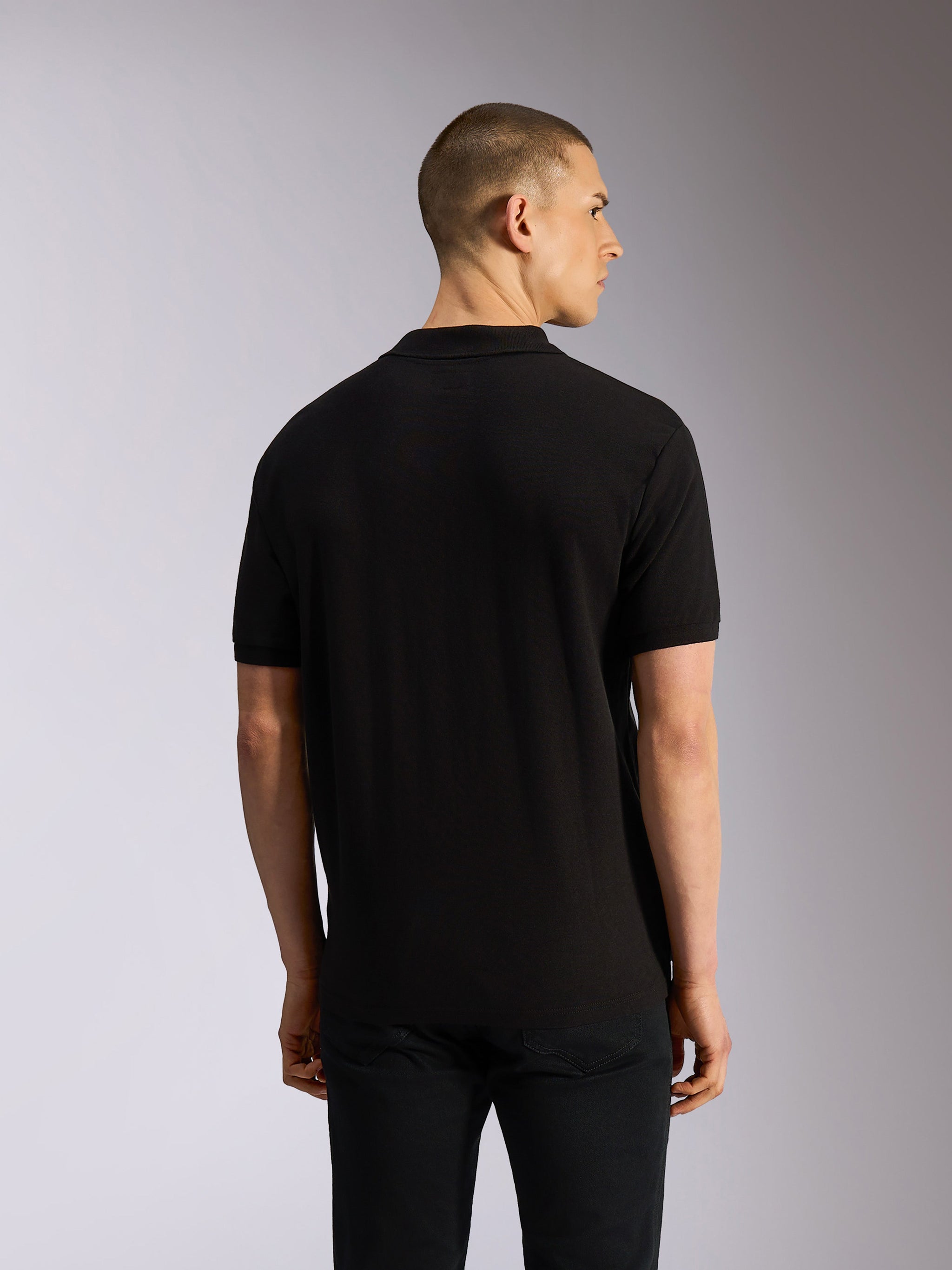 Polo Classique Alpinestars Endeavor, polo à manches courtes, noir, vue de dos sur modèle, maille piquée classique avec col et poignets en côtes, vêtement décontracté inspiré du sport automobile