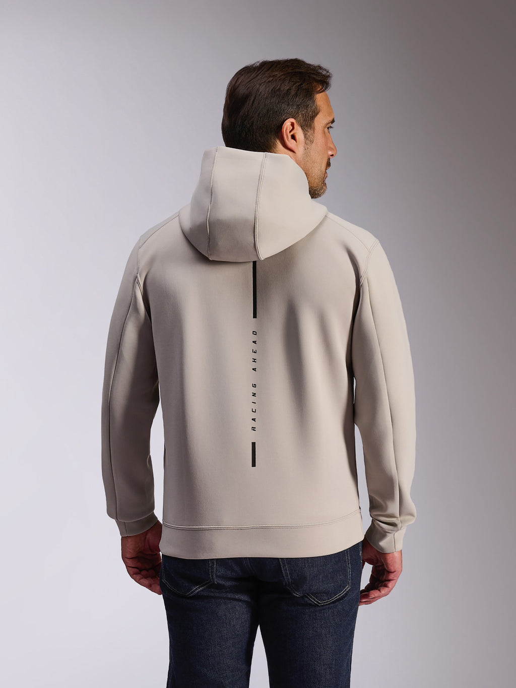 Sweat à capuche Alpinestars Insight en Cement, vue arrière d'un mannequin portant un sweat-shirt gris clair, présente un logo à bande verticale noire avec l'inscription 'RACING AHEAD', sweat à capuche décontracté en polaire double face inspiré du sport automobile.