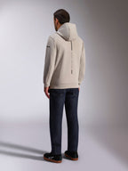 Sweat à capuche Alpinestars Insight, vue de dos en gris ciment, bande noire verticale avec le texte « RACING AHEAD », design streetwear décontracté, porté avec un jean foncé et des chaussures noires.