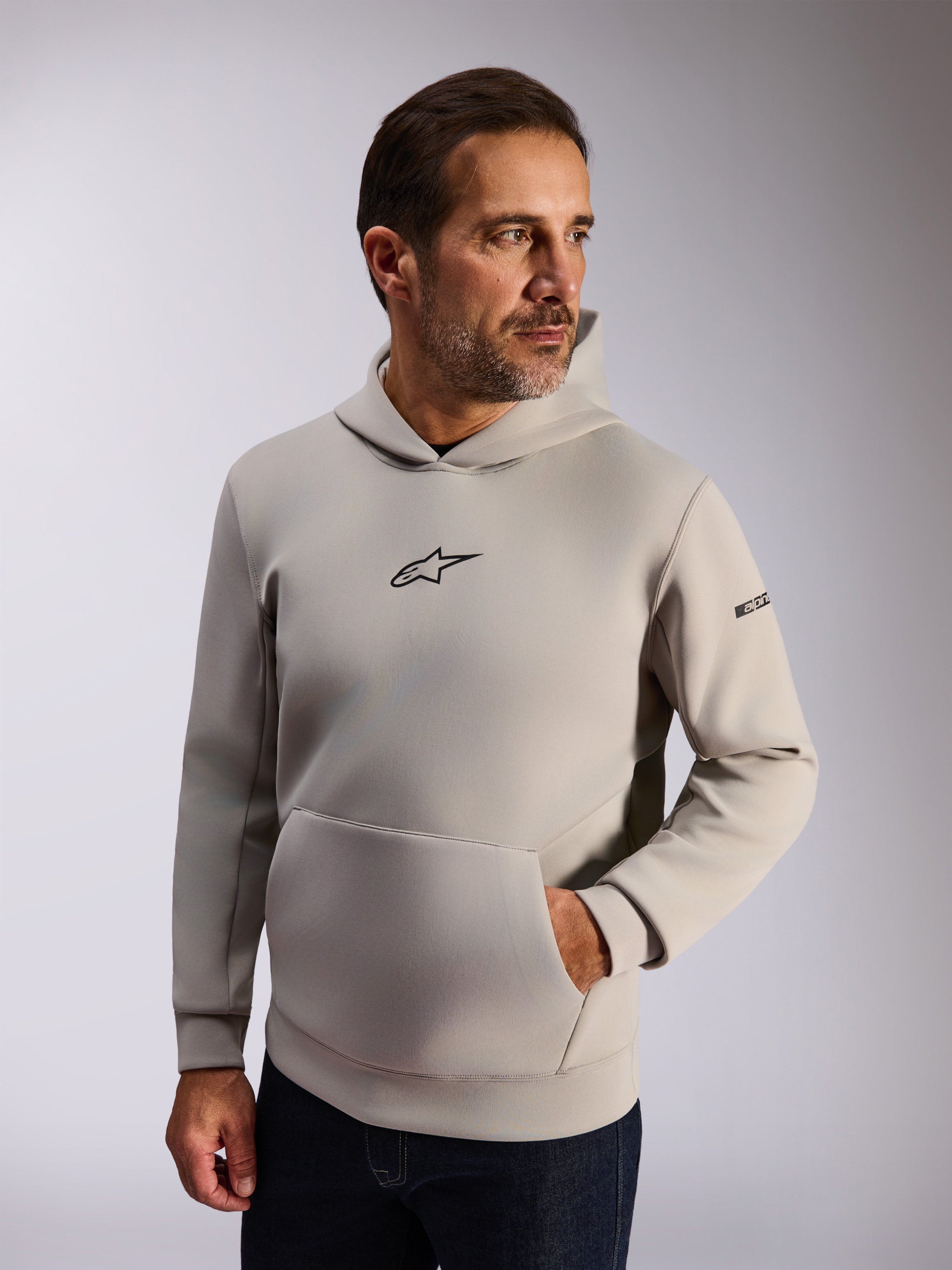 Sweat à capuche Alpinestars Insight, vêtement streetwear décontracté, polaire gris ciment, logo Astars noir à l'avant, poche kangourou, lettrage sur la manche, capuche doublée en mesh, vêtement moderne inspiré des sports mécaniques