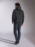 Sweat à capuche Alpinestars Emergent Oversized, noir, vue de dos montrant le logo Alpinestars en broderie 3D sur les épaules, coupe ample, porté avec un jean en denim bleu foncé et des baskets noires, streetwear décontracté inspiré du sport automobile.