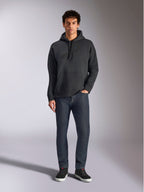 Alpinestars Emergent Oversized Hoodie, sweat à capuche de style streetwear décontracté, noir avec logo brodé en 3D ton sur ton, capuche à cordon de serrage, poche kangourou, coupe ample, porté par un mannequin avec un jean bleu foncé et des baskets noires