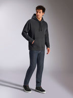 Sweat à capuche oversized Emergent Alpinestars, streetwear décontracté noir, logo Astars brodé en 3D ton sur ton sur la poitrine, poche kangourou, coupe oversized, porté par un mannequin homme avec un jean en denim bleu foncé et des baskets noires