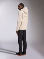 Sweat à capuche Alpinestars Emergent Oversized couleur sable, vue de dos montrant le logo Alpinestars brodé, pull en polaire oversize avec capuche, associé à un pantalon noir pour un look streetwear décontracté