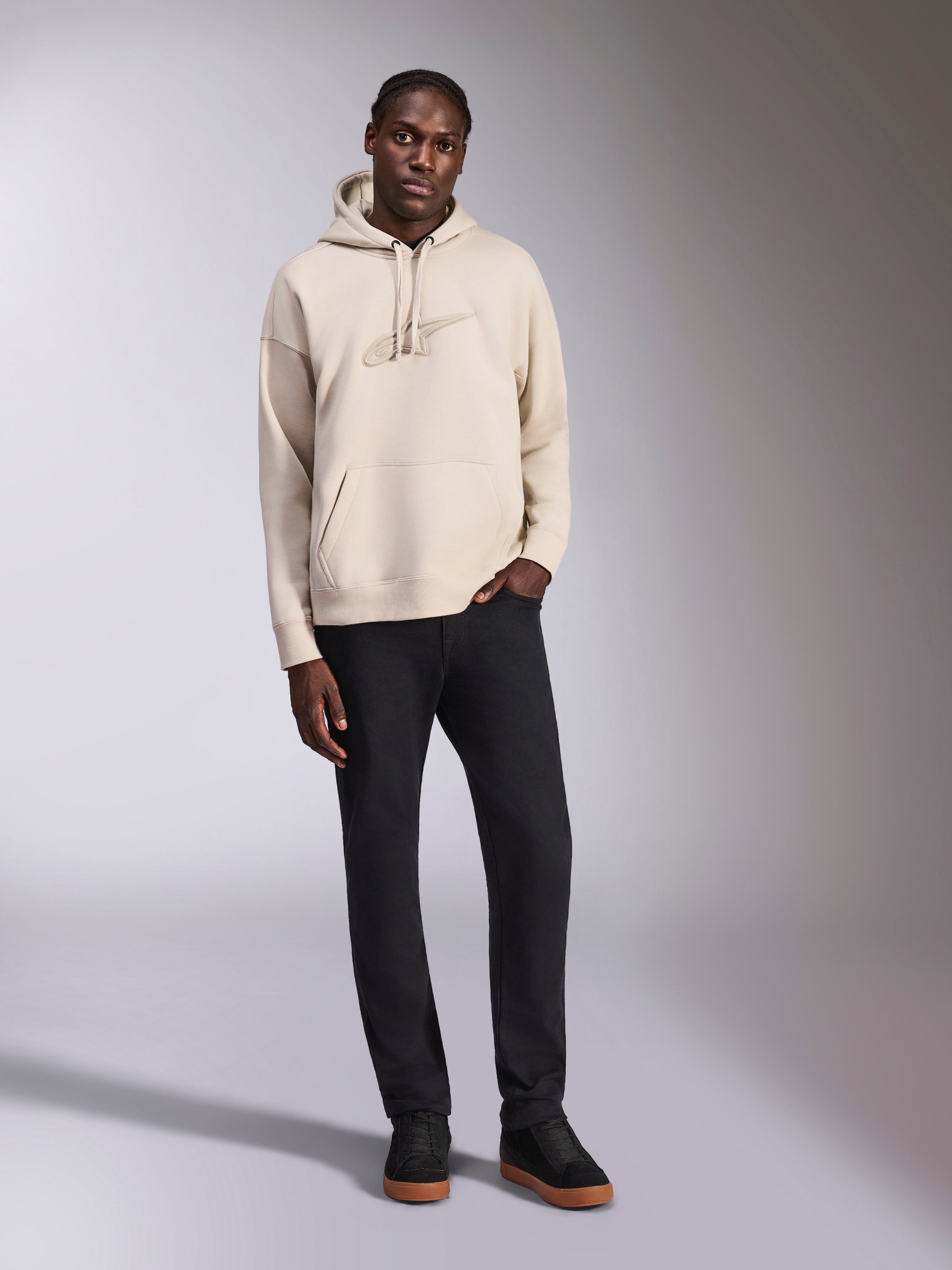 Alpinestars Emergent Oversized Hoodie, sweat à capuche en polaire, Sable, logo Astars brodé en 3D ton sur ton sur la poitrine, coupe ample avec poche kangourou et capuche à cordon de serrage, streetwear décontracté d'inspiration sport mécanique porté avec un pantalon noir