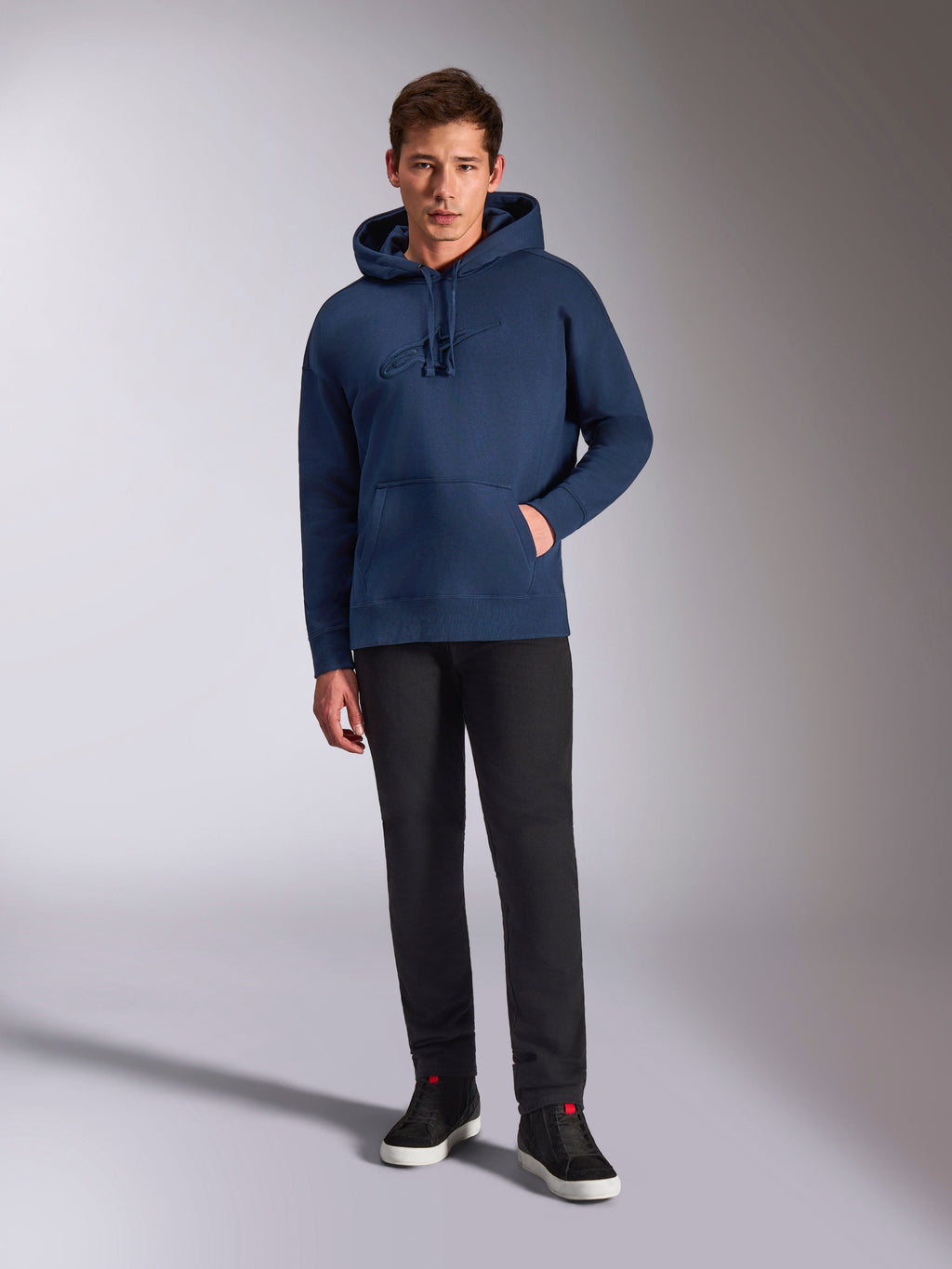 Alpinestars Emergent Oversized Hoodie, sweat à capuche en polaire bleu marine, logo brodé en 3D ton sur ton sur le devant, porté par un mannequin avec un pantalon noir et des baskets, style streetwear décontracté
