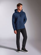 Sweat à capuche oversized Emergent Alpinestars, bleu marine, porté par un mannequin homme avec un pantalon noir et des baskets, avec logo Astars brodé en 3D, poche kangourou et capuche à cordon de serrage, style streetwear décontracté inspiré du sport automobile.