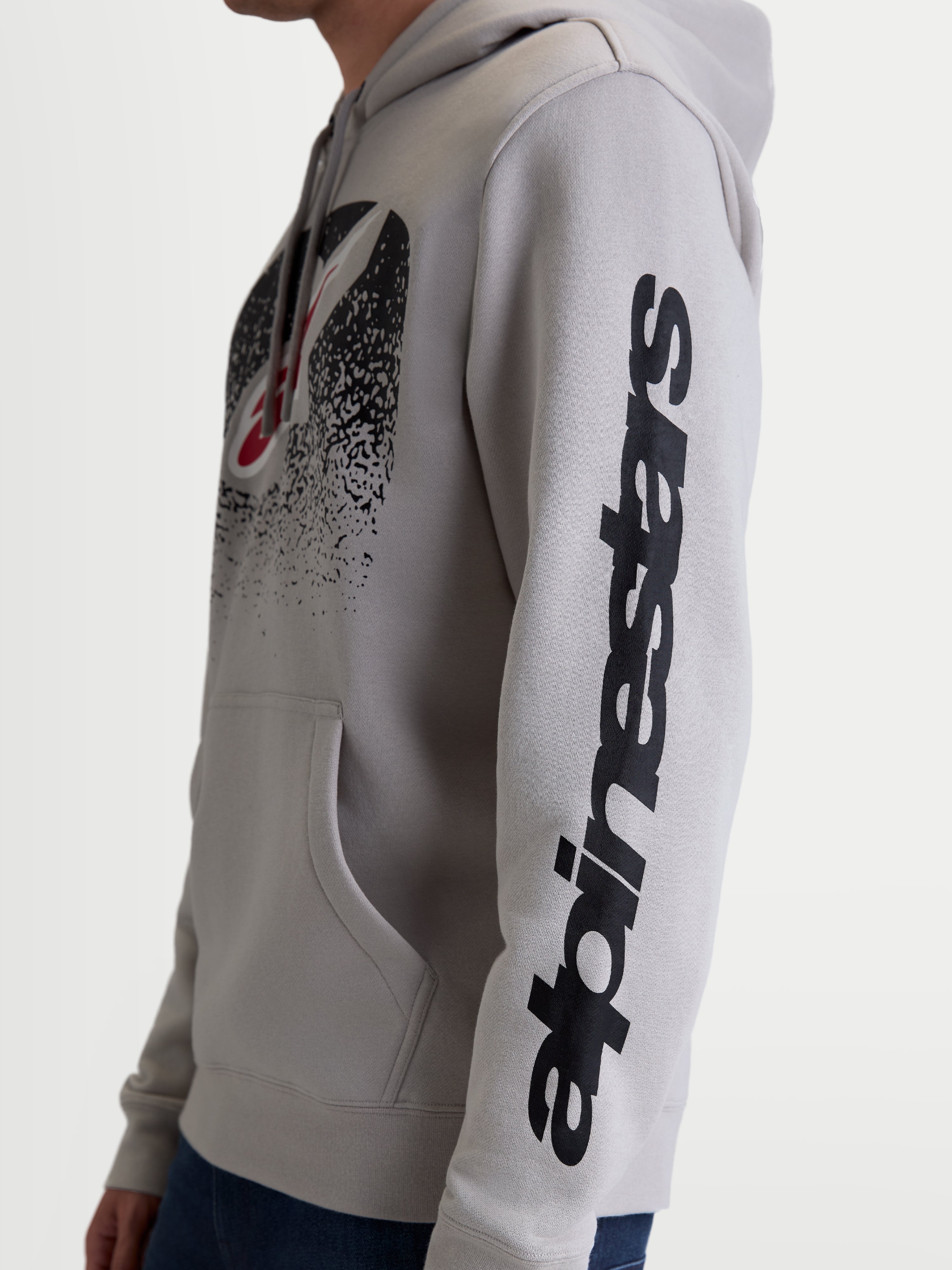 Alpinestars sweat à capuche Obsessed, pull-over en polaire sportswear unisexe, gris ciment et noir, vue de profil mettant en avant le marquage vertical Alpinestars sur la manche et le logo de poitrine dégradé inspiré du MX, construction en coton et polyester recyclé