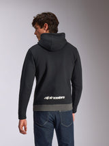 Sweat à capuche Alpinestars Parallel, sweat à capuche sportswear décontracté, noir et gris Gunmetal, vue de dos avec logo Alpinestars blanc dans le bas du dos, design en blocs de couleur avec ourlet gris, porté avec un jean en denim foncé