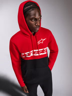 Alpinestars Parallel Hoodie, sweat à capuche décontracté en polaire, design à blocs de couleurs rouge et noir, logo Alpinestars Word et logo Astars blancs sur la poitrine, porté par un homme avec la capuche relevée et un pantalon noir, streetwear d'inspiration sport mécanique