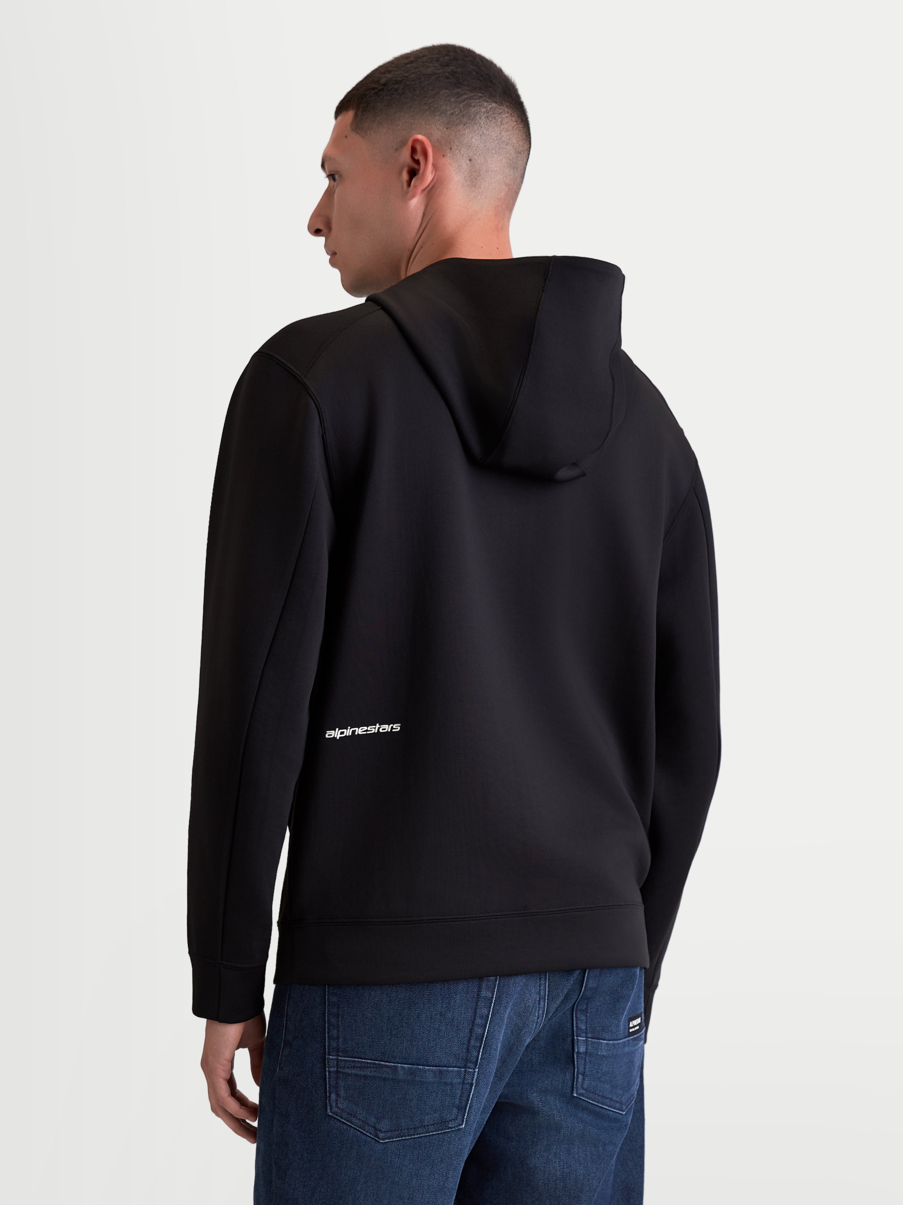 Alpinestars sweat à capuche Cypher, sweat à capuche sportswear pour homme, noir, polaire double face, vue de dos sur un modèle avec capuche à col haut et logo Alpinestars blanc en bas du dos.
