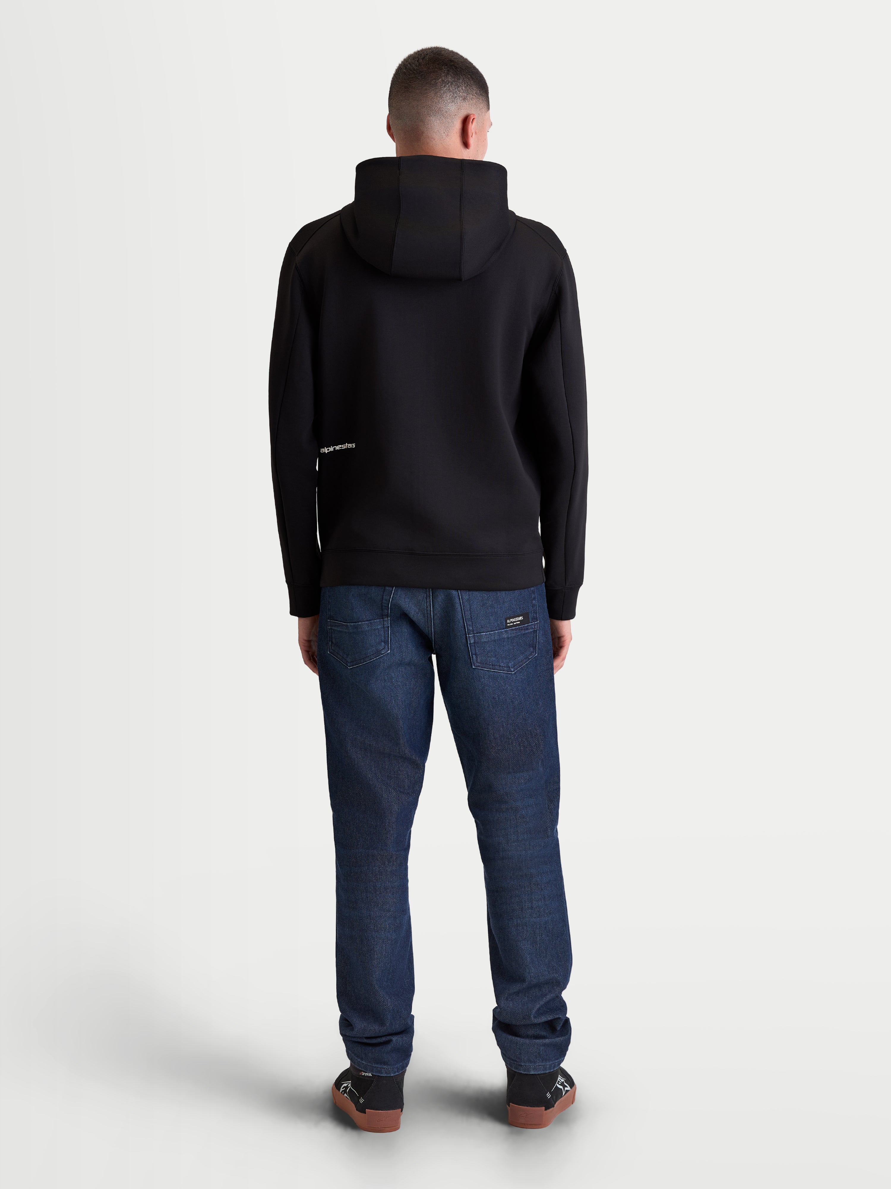 Alpinestars Sweat à capuche Cypher, sweat à capuche de sportswear noir, vue de dos sur modèle avec capuche à col haut et logo minimaliste, tissu technique tri-mélange, style streetwear et lifestyle motorsports unisexe