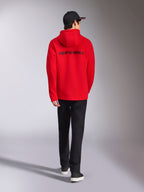Sweat à capuche Transverse Alpinestars, vêtement urbain décontracté rouge, vue arrière avec logo Alpinestars noir, veste en polaire à capuche, porté avec une casquette noire et un pantalon noir