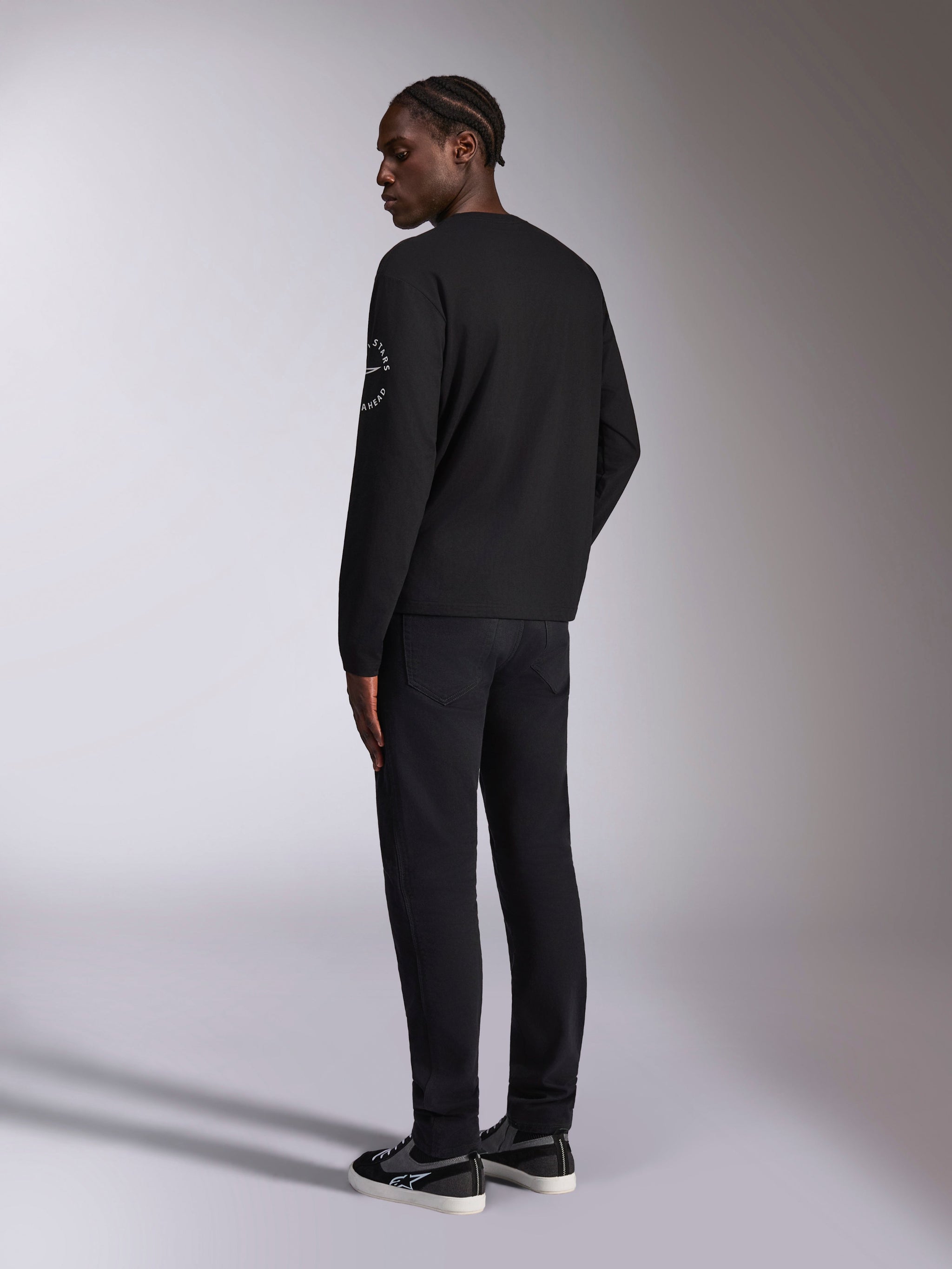 Alpinestars Mandatory CSF Long Sleeve Tee, Black, back view of model wearing long-sleeve t-shirt with white Astars circle logo on the sleeve, paired with black pants, casual motorsport streetwear