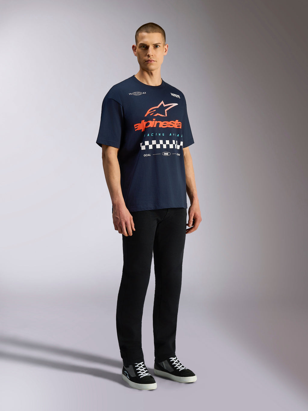 T-shirt Alpinestars Aplomb CSF Oversized, manches courtes, bleu marine, grand logo Astars orange et blanc avec motif à damier, style streetwear décontracté inspiré des sports mécaniques
