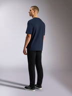 T-shirt Alpinestars Aplomb Oversized CSF, t-shirt à manches courtes, bleu marine, vue de dos sur mannequin, porté avec un pantalon noir et des baskets, streetwear décontracté d'inspiration sport automobile