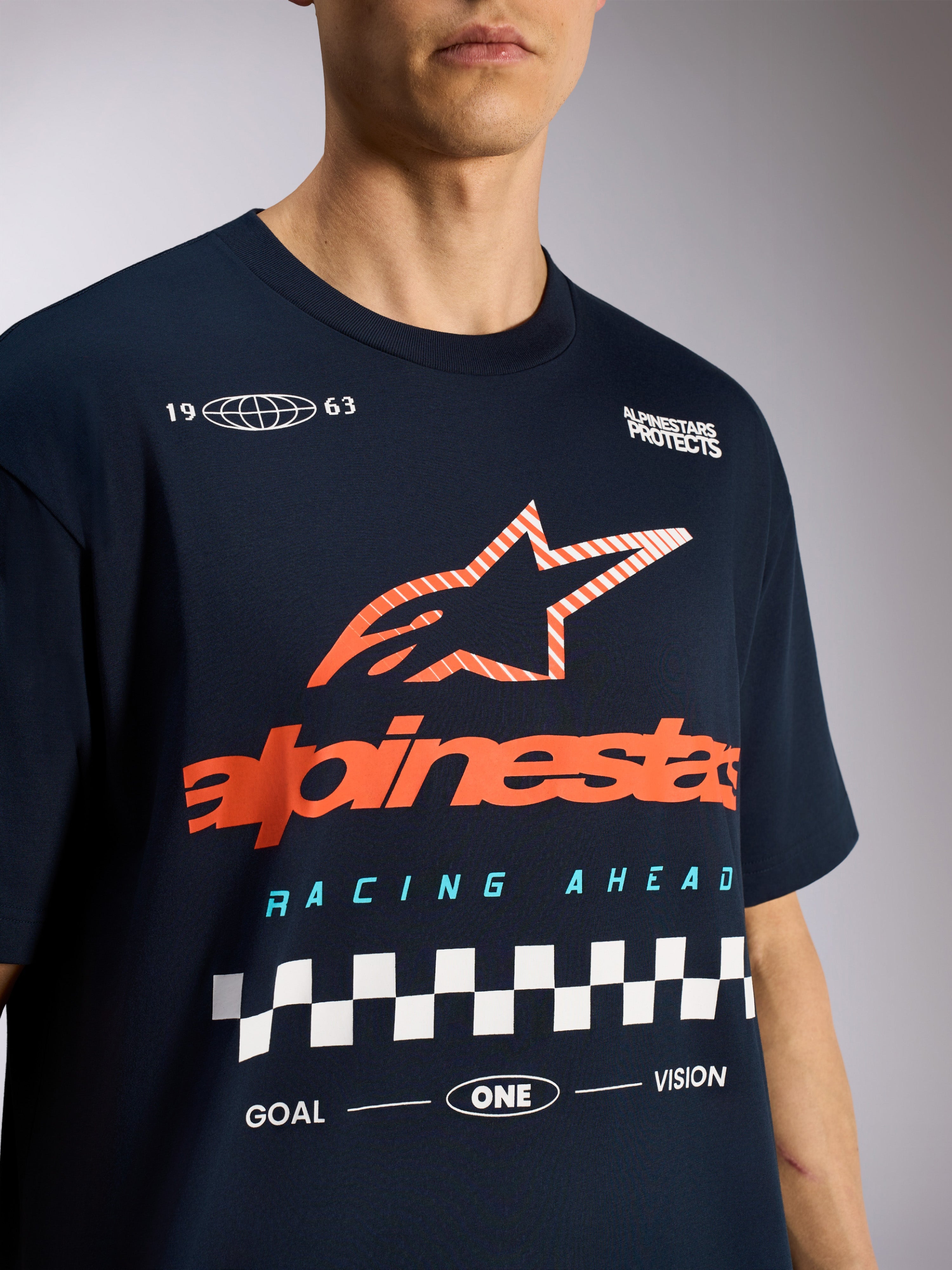 Alpinestars Aplomb Oversized CSF Tee, t-shirt à manches courtes, bleu marine, arborant un grand logo étoile Astars à rayures orange et un motif de course à damier, vêtement de sport décontracté Motorsport
