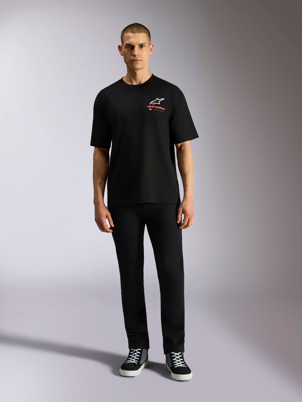 T-shirt Alpinestars Overhang Oversized CSF, t-shirt à manches courtes, noir, logo Astars blanc avec texte rouge, porté par un mannequin avec un pantalon noir et des baskets, style streetwear décontracté inspiré du sport automobile
