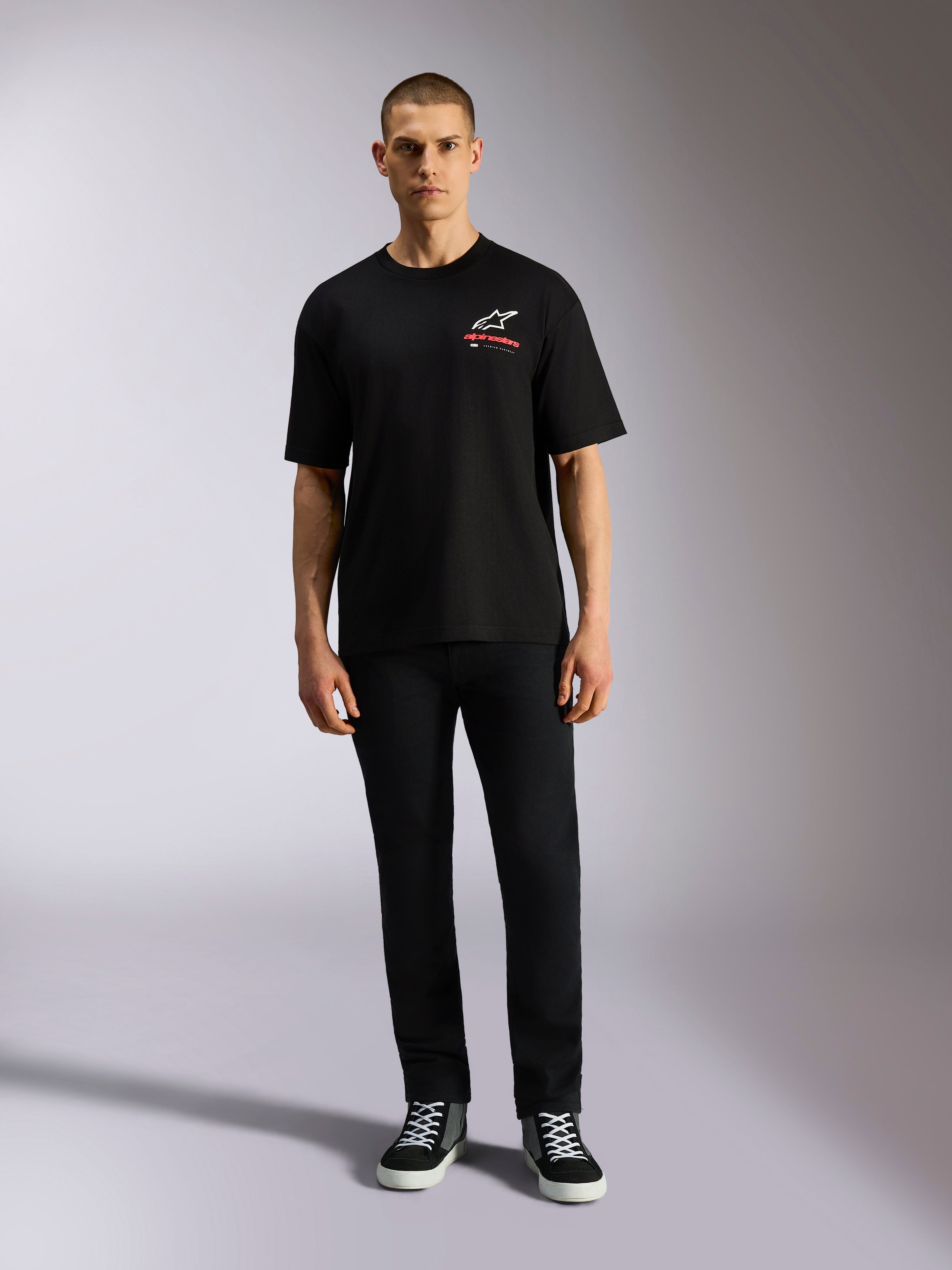 T-shirt Alpinestars Overhang Oversized CSF, t-shirt à manches courtes, noir, logo Astars blanc avec texte rouge, porté par un mannequin avec un pantalon noir et des baskets, style streetwear décontracté inspiré du sport automobile