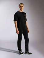 T-shirt Alpinestars Overhang Oversized CSF, manches courtes, noir, avec logo Astars blanc et rouge à l'avant, porté par un mannequin avec un pantalon noir et des baskets, design streetwear casual ample