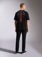 Alpinestars Overhang Oversized CSF Tee, t-shirt à manches courtes, noir, avec lettrage vertical rouge Alpinestars et graphique circulaire gris au dos, porté par un modèle de dos, style streetwear décontracté