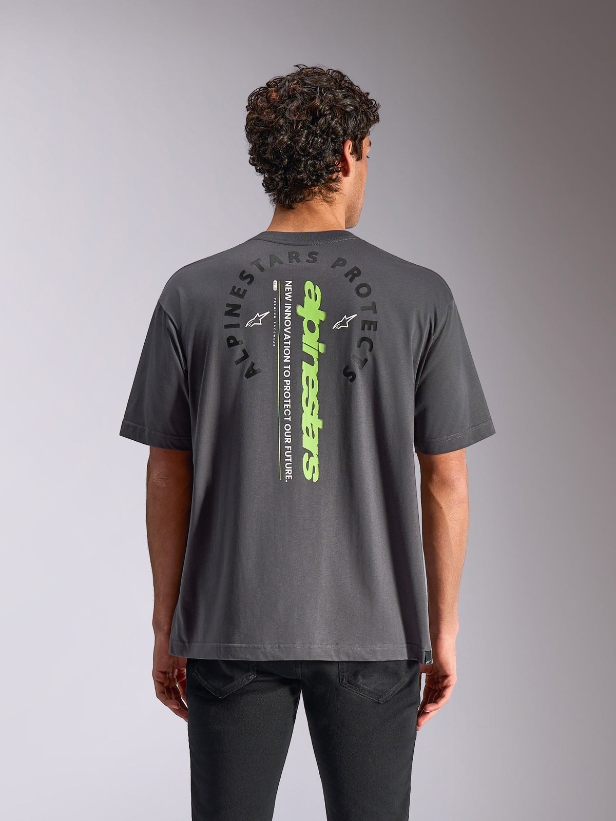 Alpinestars Overhang Oversized CSF Tee, t-shirt à manches courtes, gris anthracite, vue de dos avec mot-symbole vertical vert fluo et graphique circulaire, coupe surdimensionnée décontractée, style streetwear motorsport décontracté