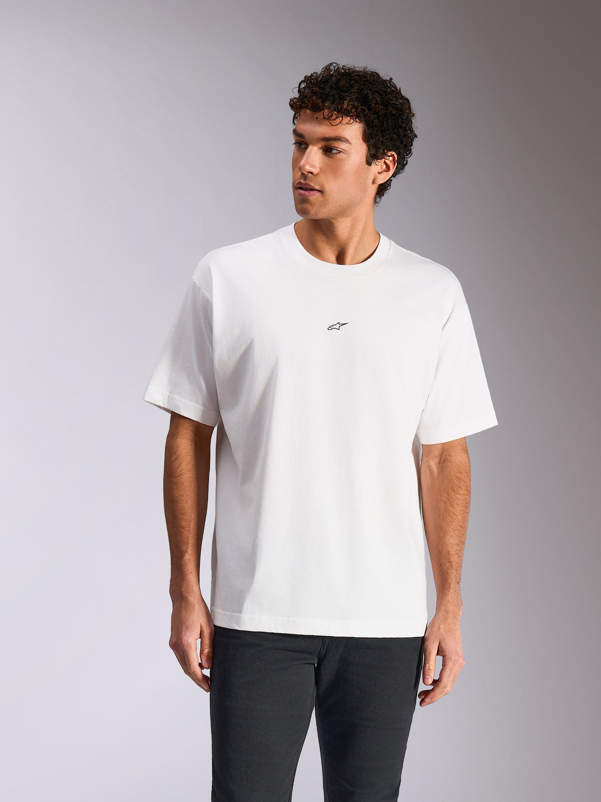 T-shirt Alpinestars Focused Oversized CSF, t-shirt à manches courtes, blanc, petit logo Astars noir sur la poitrine, coupe décontractée portée par un mannequin, style streetwear motorsport décontracté