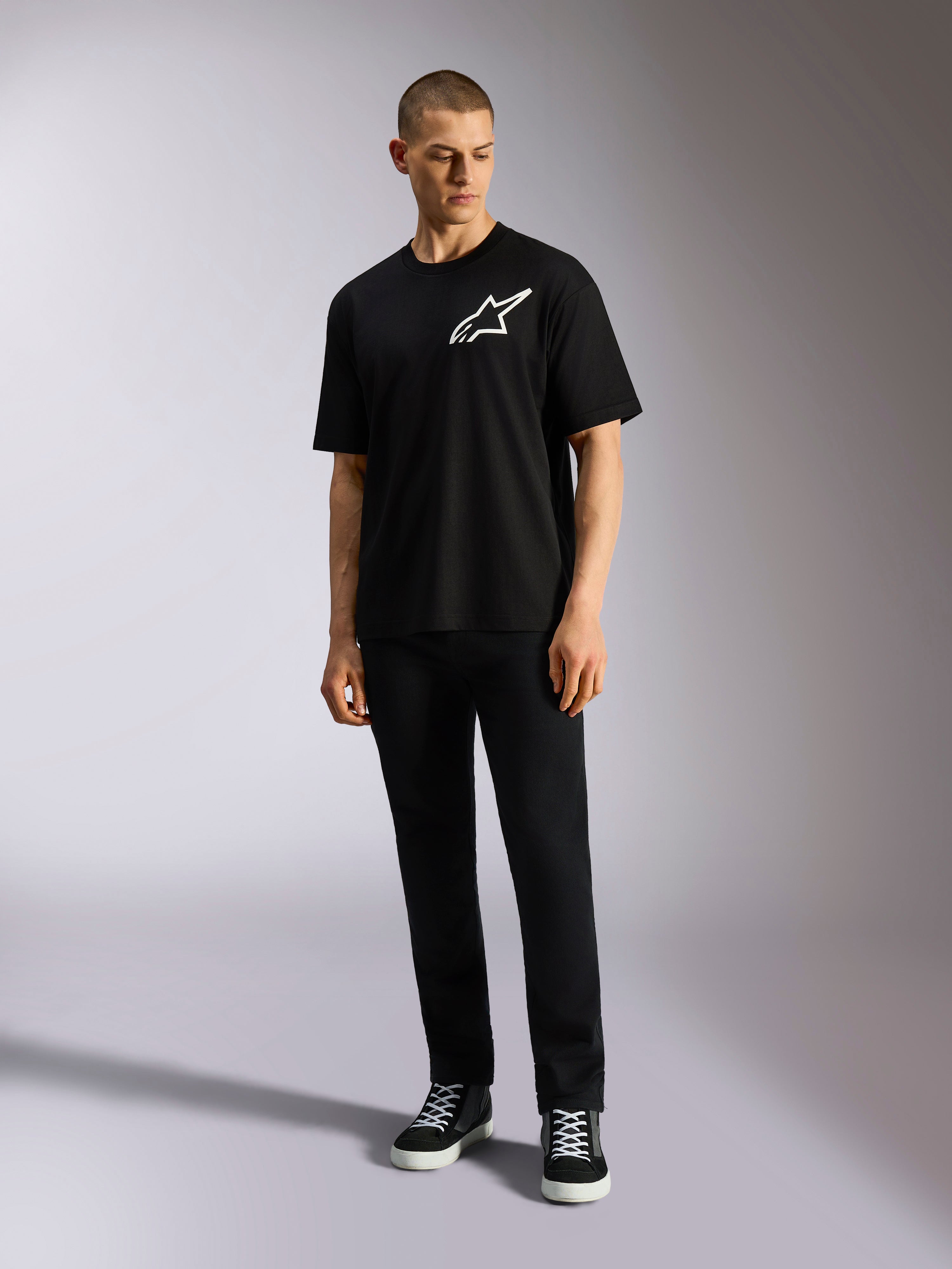 T-shirt Alpinestars One Oversized CSF, t-shirt à manches courtes, noir, logo Astars blanc sur la poitrine, coupe surdimensionnée, porté par un mannequin avec un pantalon noir et des baskets, style streetwear décontracté